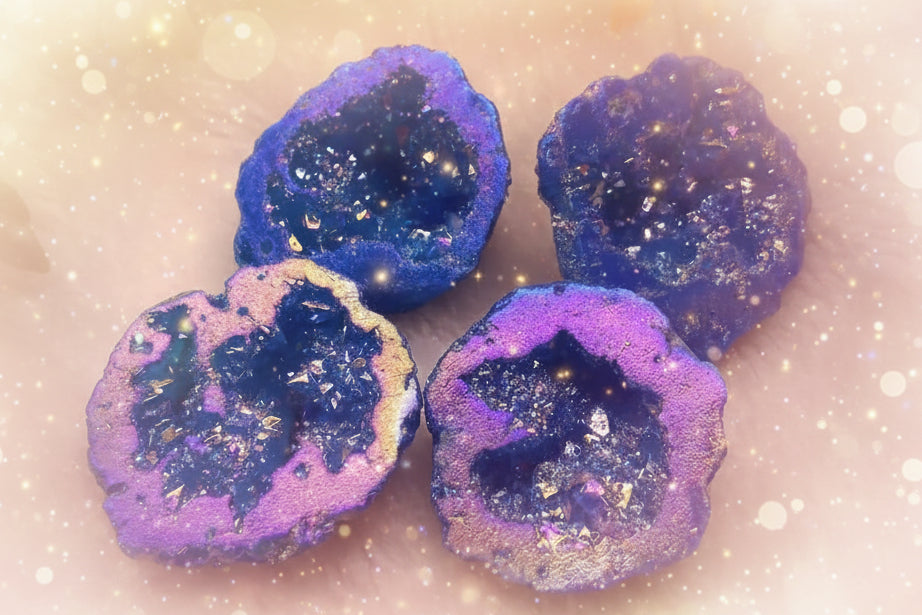 Blue and purple geode-like objects on a white surface with flowers in the background