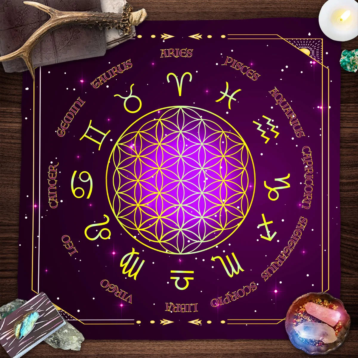 Purple mat with zodiac symbols on a wooden surface with crystals and a candle.
