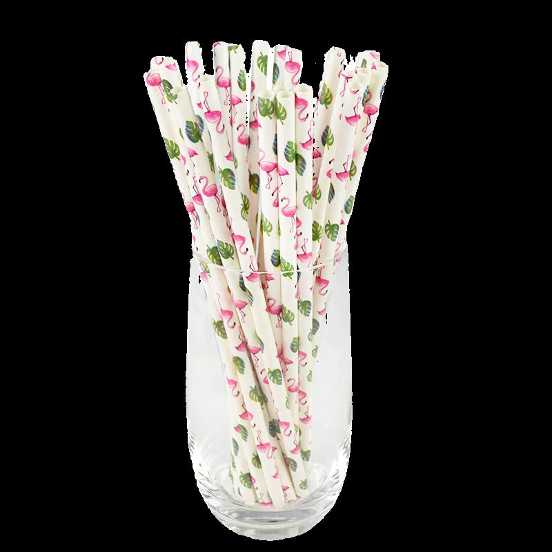 Set of decorative paper straws with flamingo and pineapple pattern in a clear glass vase on a white background
