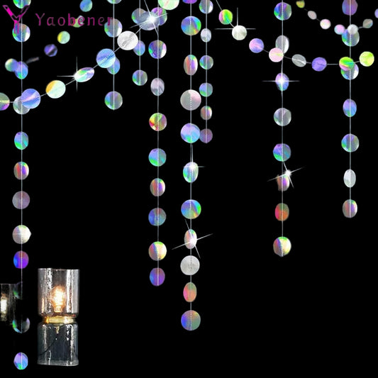Iridescent round decorations hanging against a dark wall with candles on a shelf.