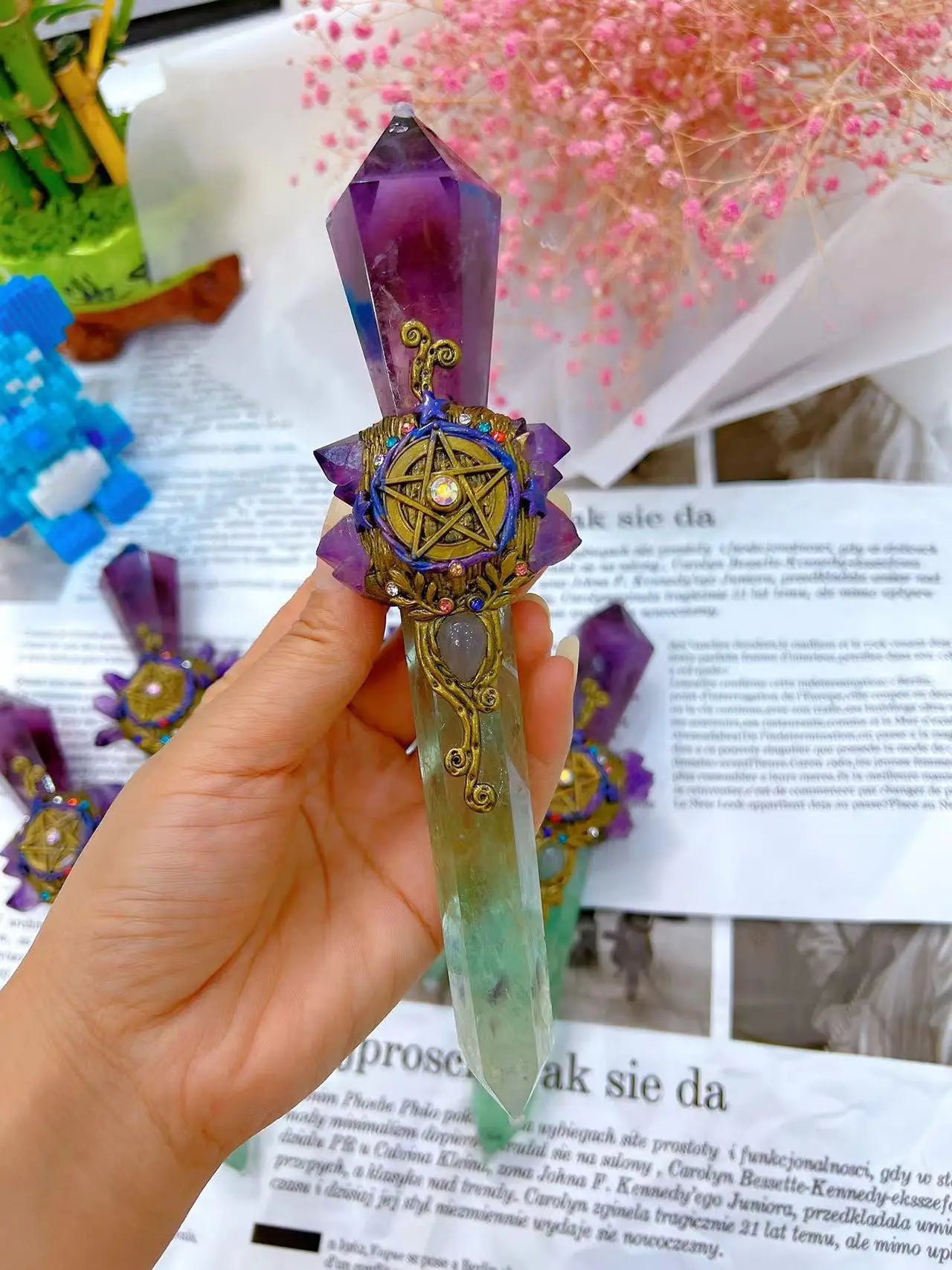 Crystal with decorative element held by a hand against a magazine background