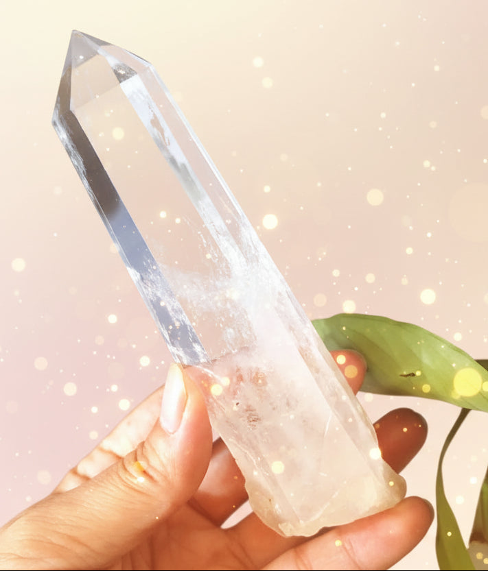 Clear crystal held by a hand with a dark background