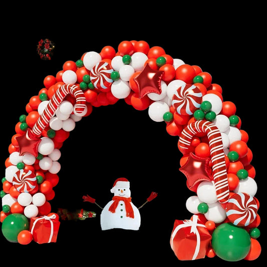 Christmas-themed balloon arch with candy decorations on a snowy porch.