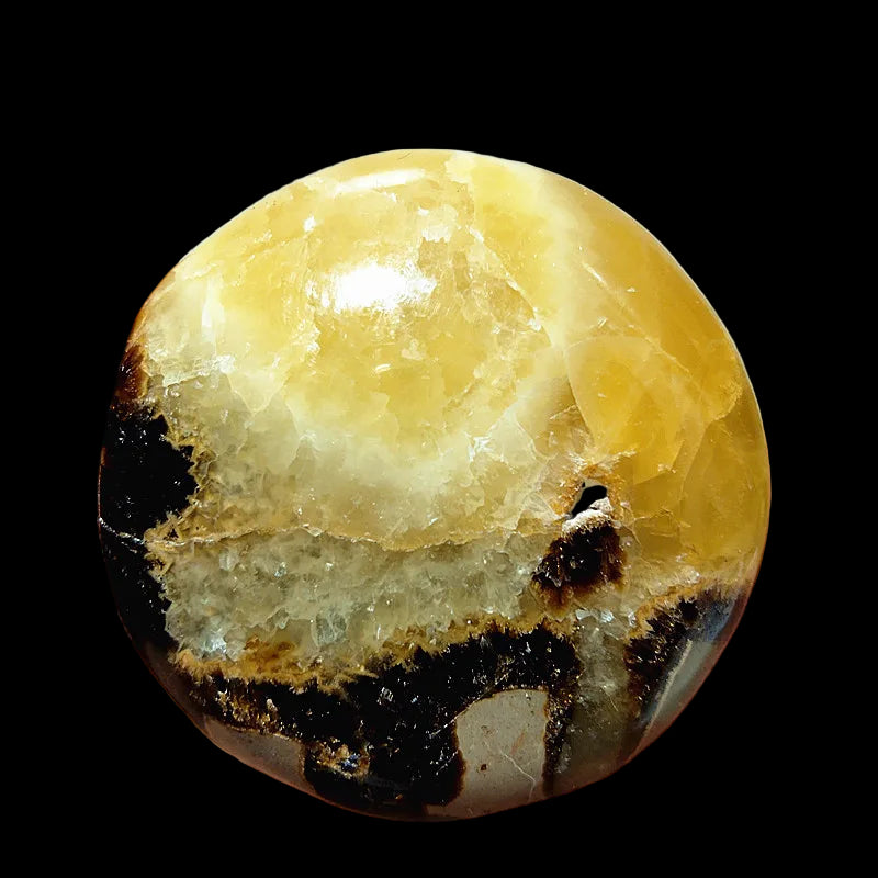 Hand holding a yellow and black marbled stone against a white background