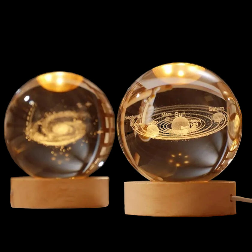 Two illuminated crystal balls with solar system designs on wooden bases against a dark background.