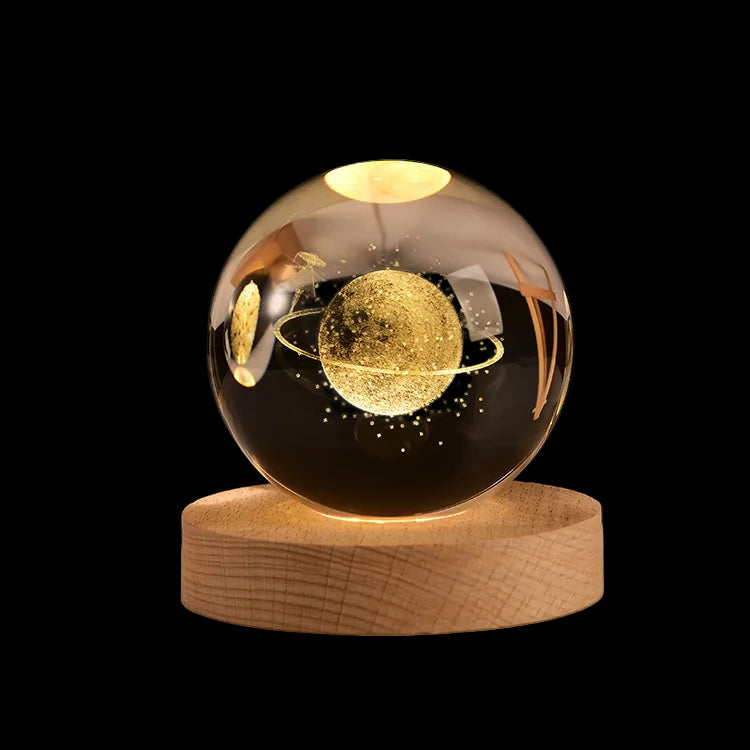Decorative glass sphere with gold planet design on a wooden base against a dark background