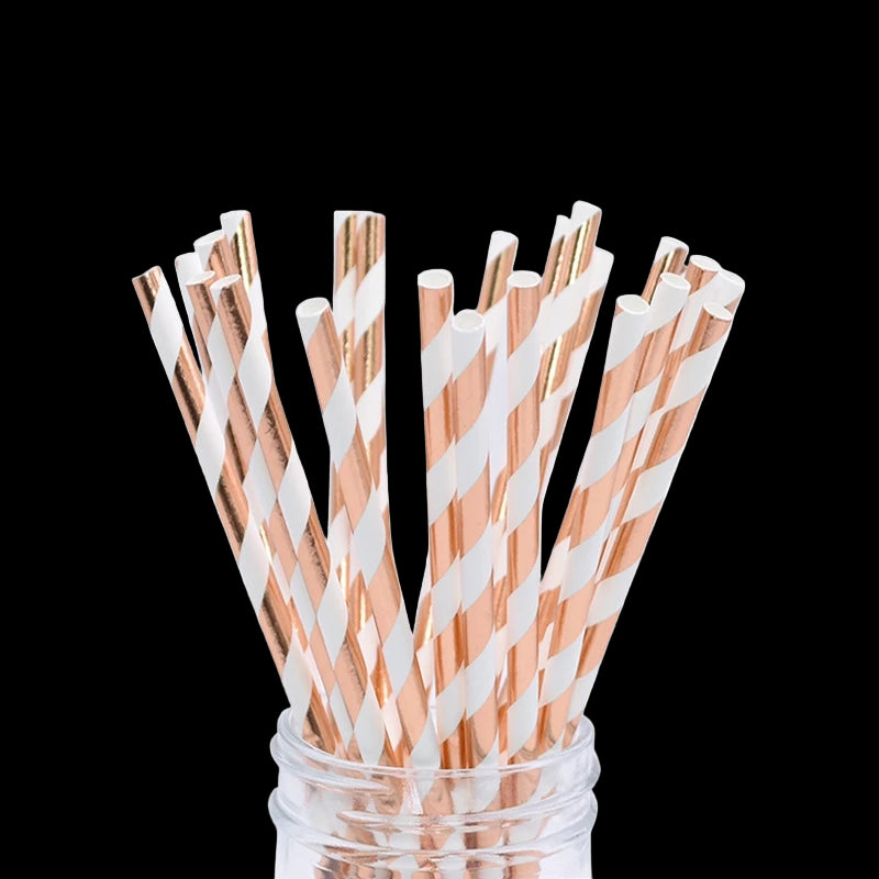 Rose gold and white striped paper straws in a glass jar on a white background