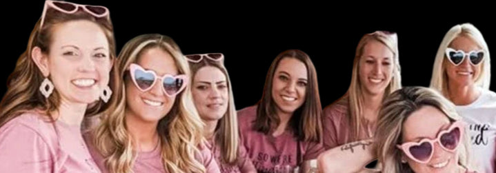 Group of women wearing pink t-shirts sitting outdoors at a table.
