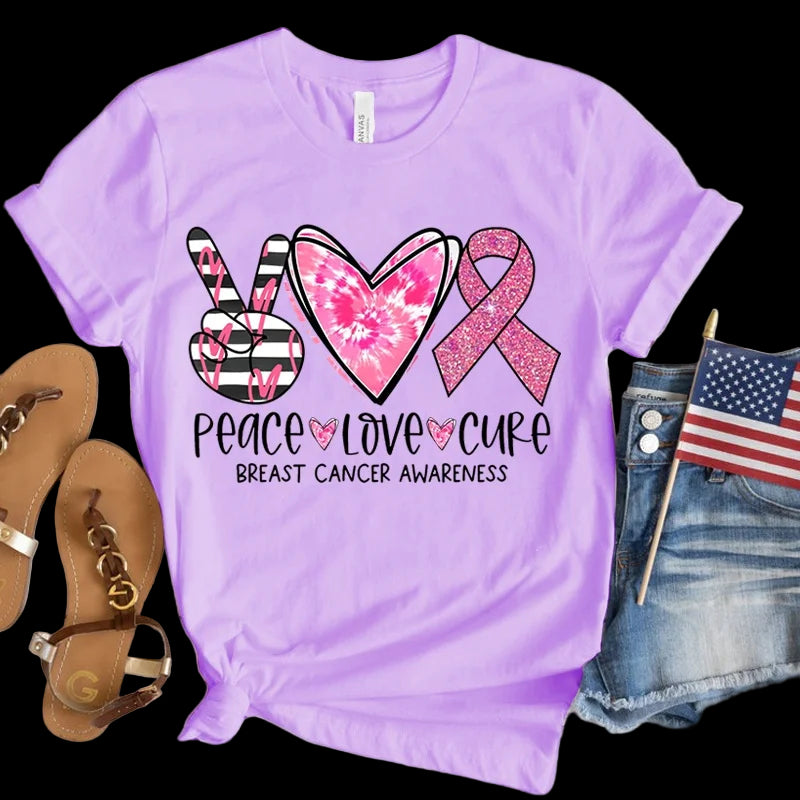 Purple t-shirt with breast cancer awareness design featuring a peace sign, heart, and pink ribbon on a wooden surface.