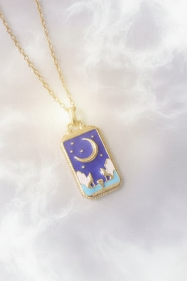 Gold necklace with a blue pendant featuring a moon and star design on a textured surface.