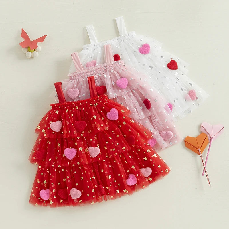 Two children's dresses, one red with heart patterns and the other white with star patterns, on a light background.