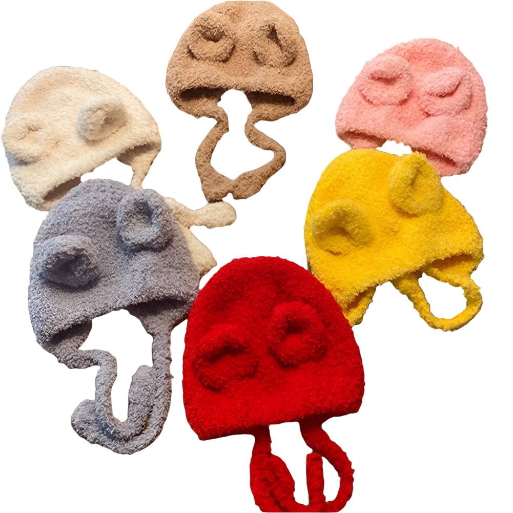 Set of colorful knitted hats with animal ears on a wooden surface
