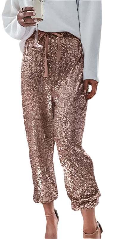 Person wearing rose gold sequin pants and a white top, standing on a sidewalk.