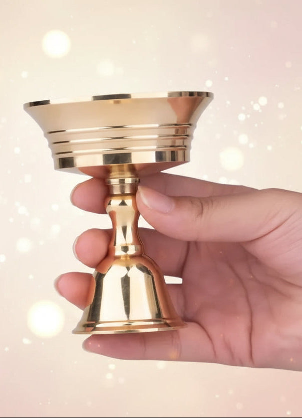 Hand holding a gold candle holder against a black background