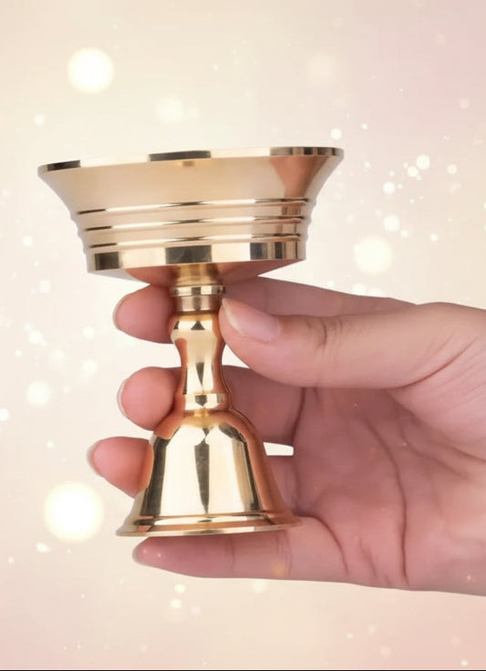 Hand holding a gold candle holder against a black background