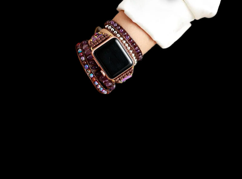 Smartwatch with a decorative purple band worn on a wrist, with a blurred background.
