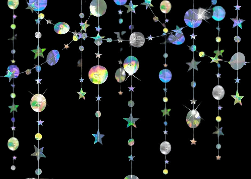 Decorative string with colorful stars and circles hanging against a dark wall.