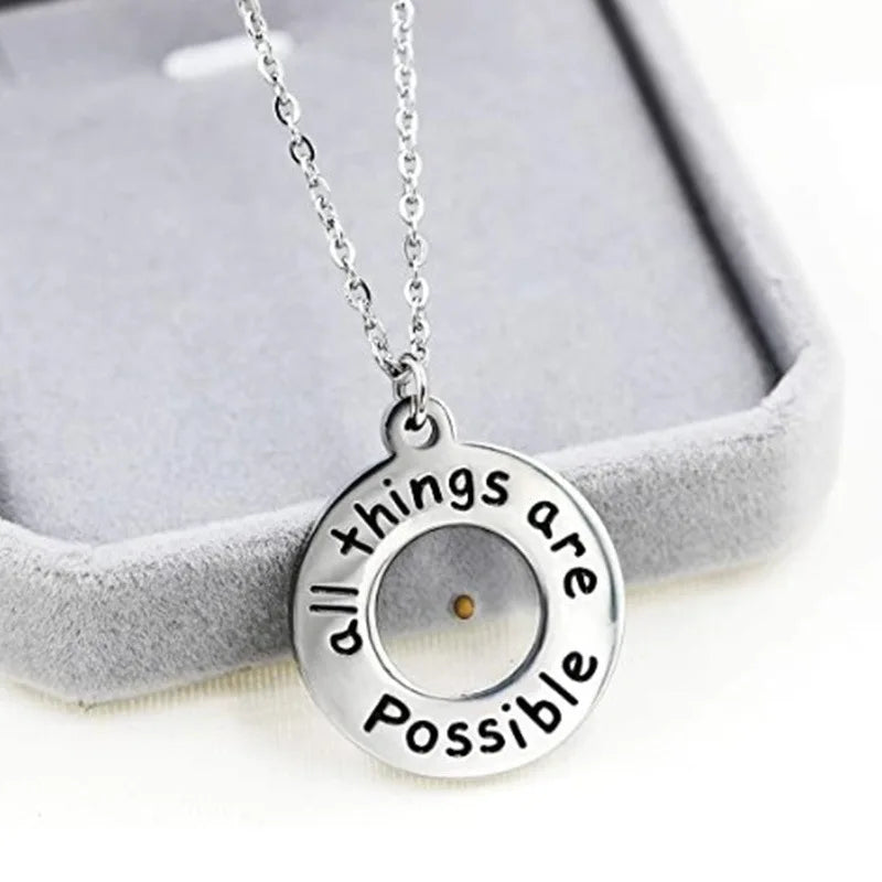 Silver necklace with a pendant that says 'All things are possible' on a gray background