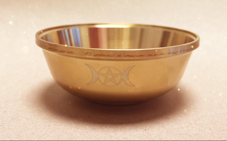 Gold bowl with engraved design on a beige background