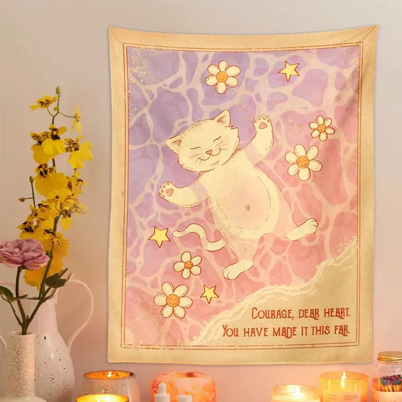 Decorative wall tapestry with a cat illustration and motivational quote, placed on a wall with candles and flowers.