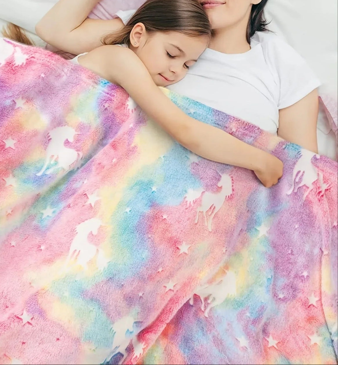 Woman and child under a colorful blanket with unicorn pattern