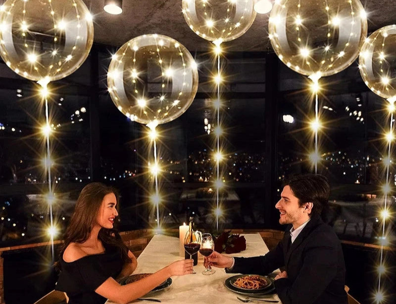 Couple dining together with decorative balloons and lights in a restaurant.