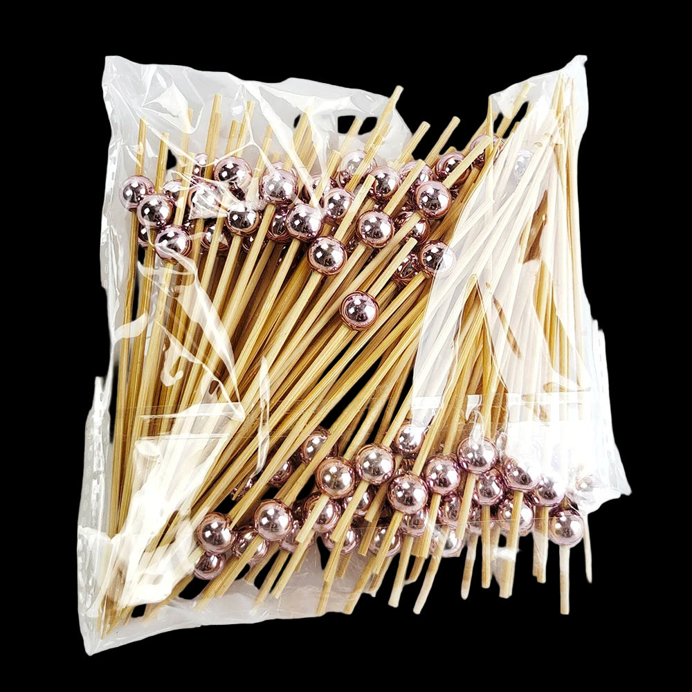 Packaged toothpicks with rose gold beads on a white background
