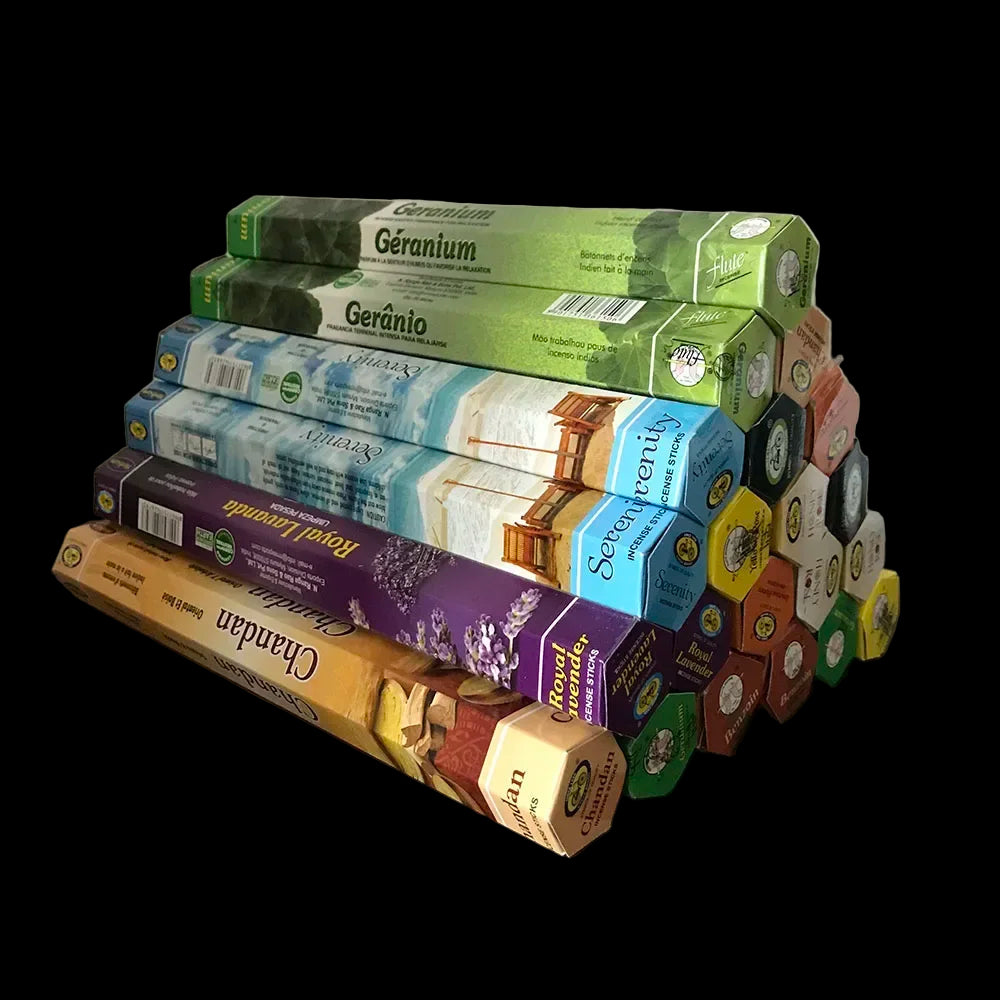 Stack of incense boxes and sticks on a wooden surface with a white background
