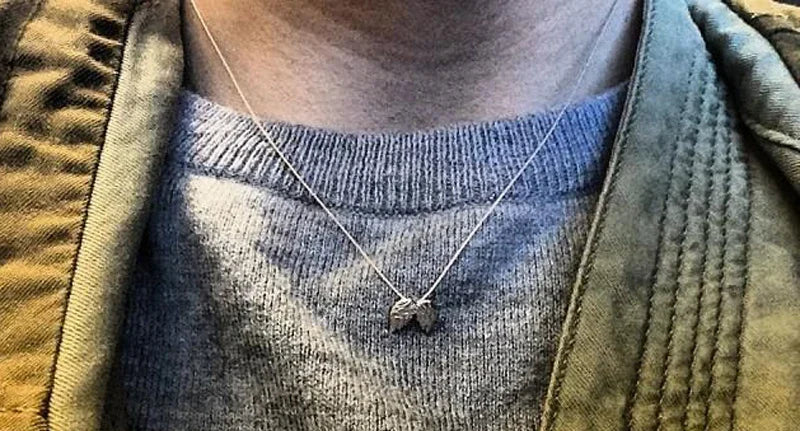 Person wearing a necklace with a pendant, partially covered by a jacket.
