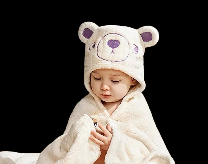 Child wearing a bear-themed hooded towel, sitting on a couch with a soft focus background.