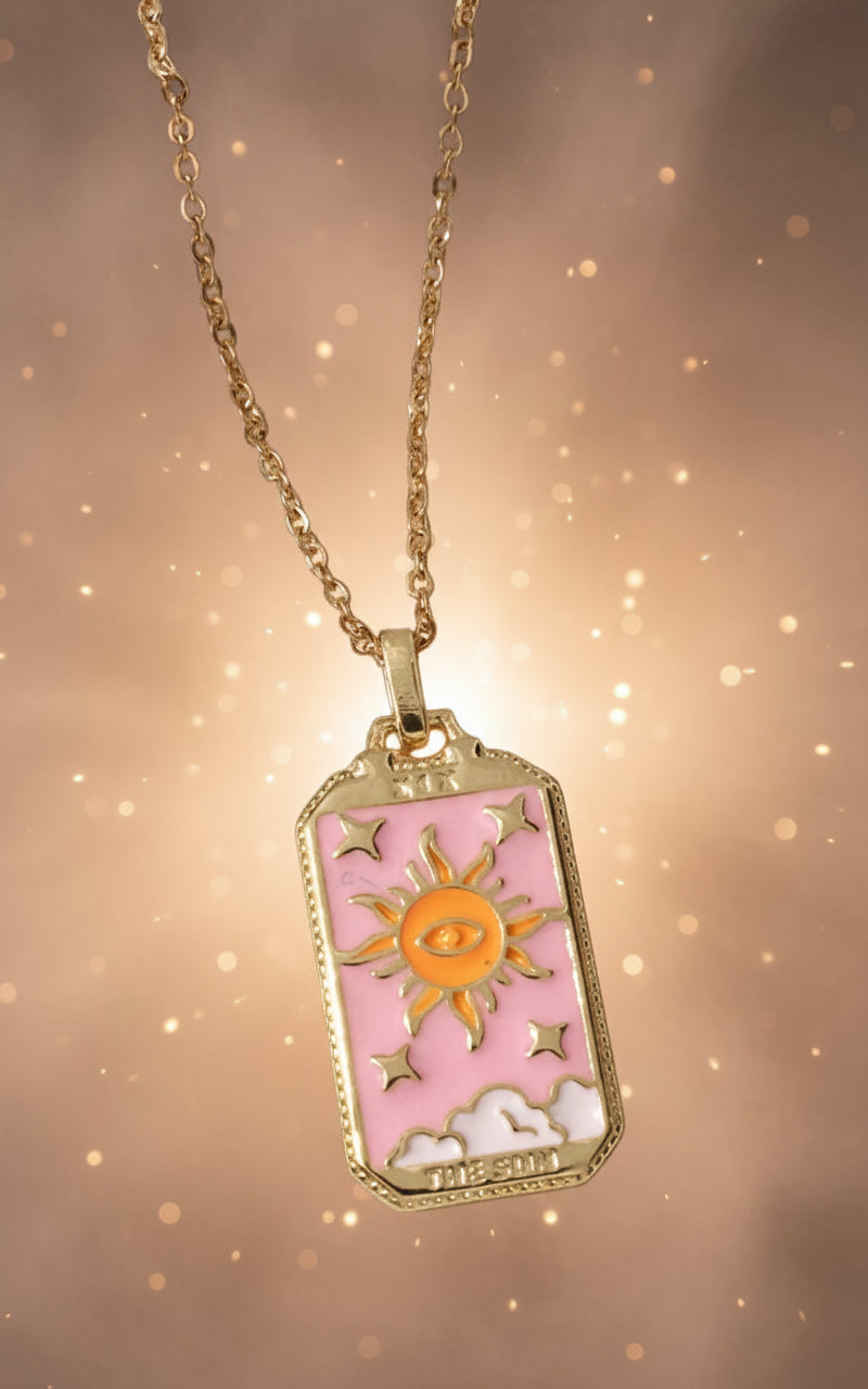 Necklace with a sun and cloud pendant on a textured beige surface