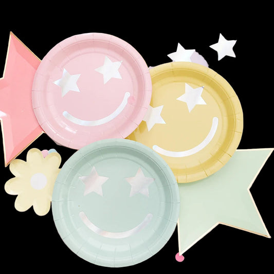 Pastel-colored paper plates with smiley face and star designs on a light background.