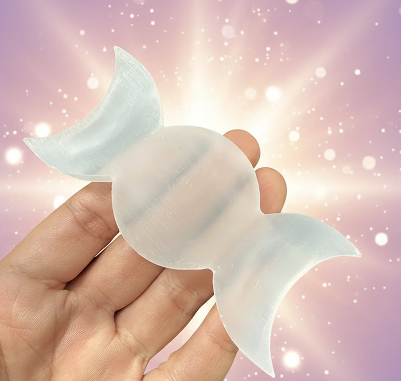 Hand holding three white moon-shaped objects against a black background