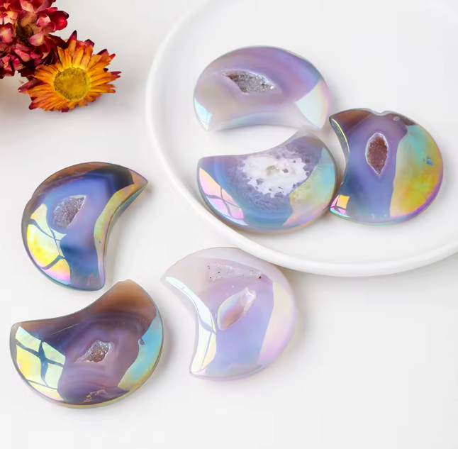 Iridescent crystal-like objects on a white plate with flowers in the background