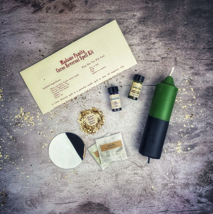 Witchcraft kit with green candle, envelope, and small bottles on a textured surface