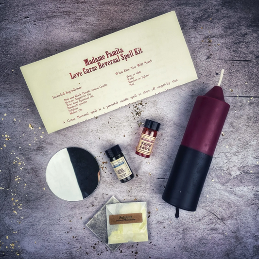 Spells kit with candles, oils, and a letter on a textured surface