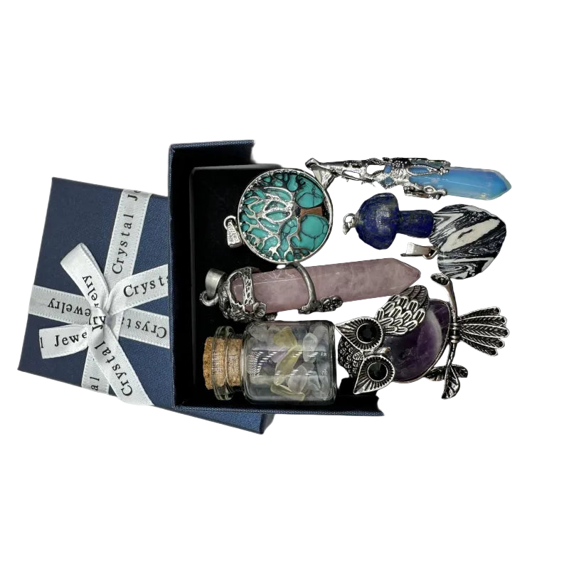 Crystal jewelry set with necklaces and amulets in a black box, next to a branded gift bag.