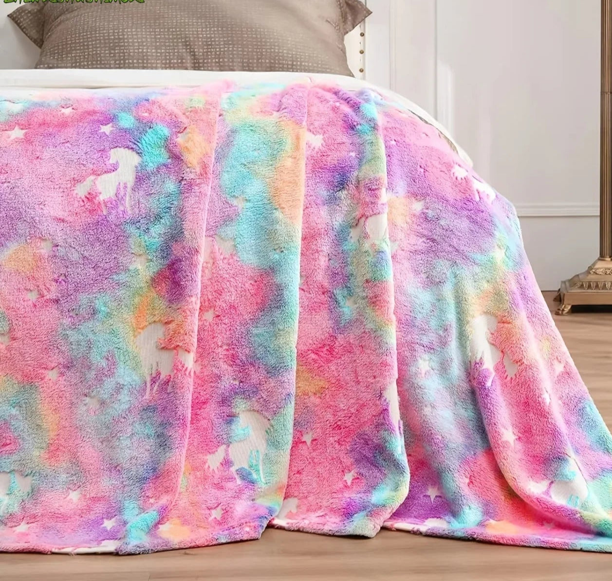Colorful tie-dye blanket draped over a bed in a bedroom setting.