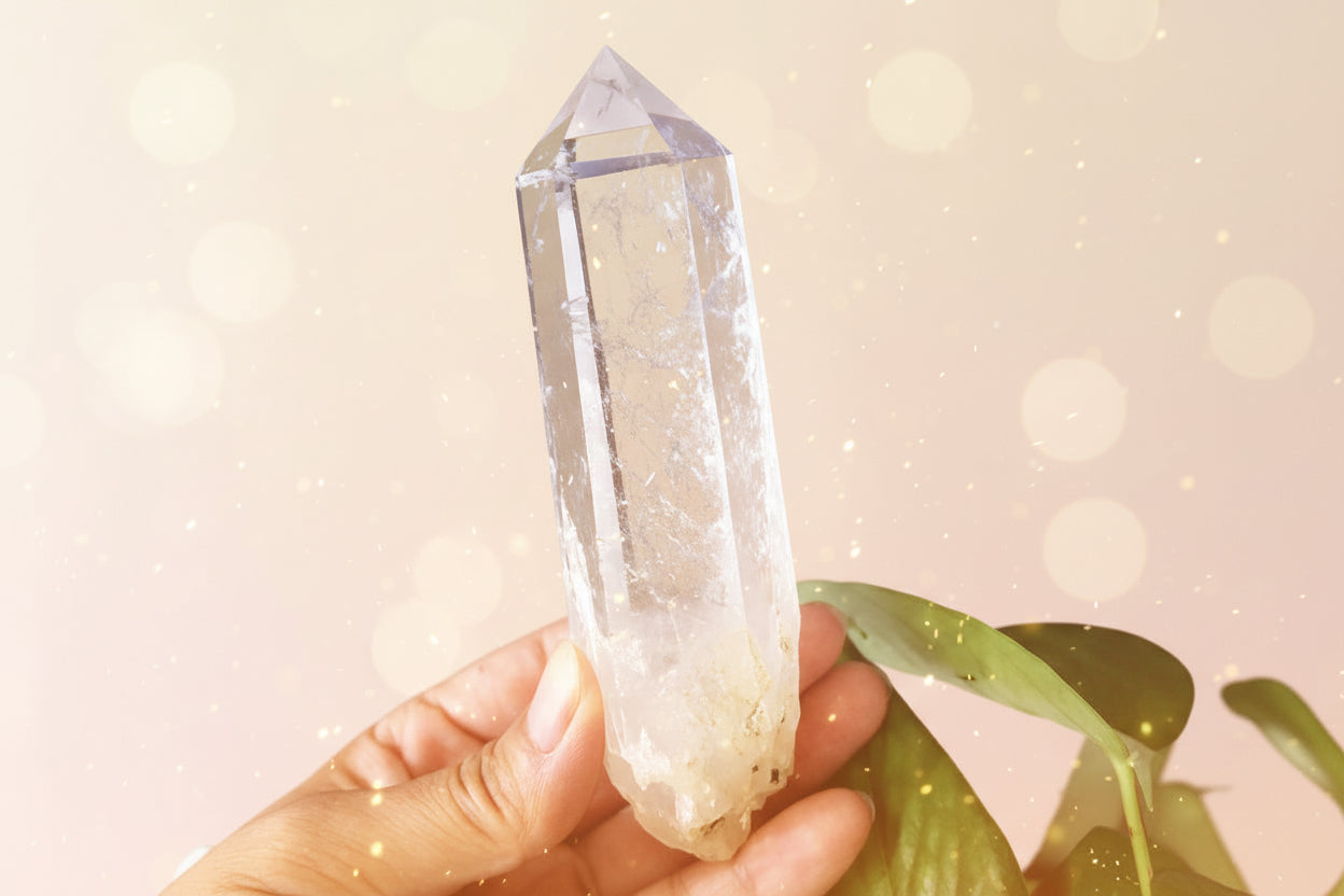 Clear crystal held by a hand with a dark background