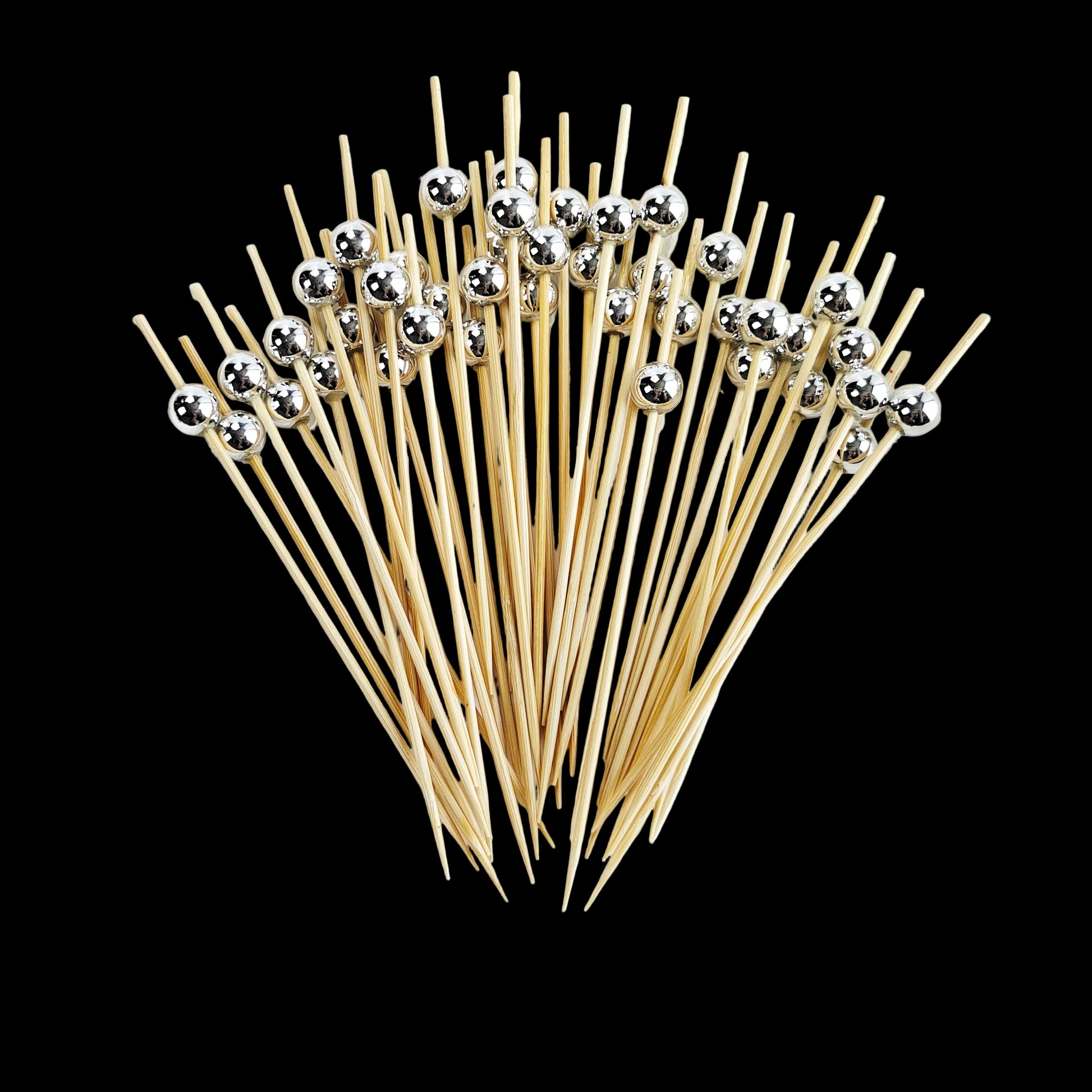 Wooden skewers with silver beads on a white plate