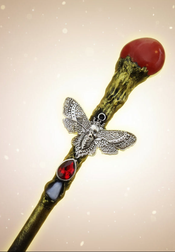 Decorative hair stick with butterfly and red gemstone on a dark background