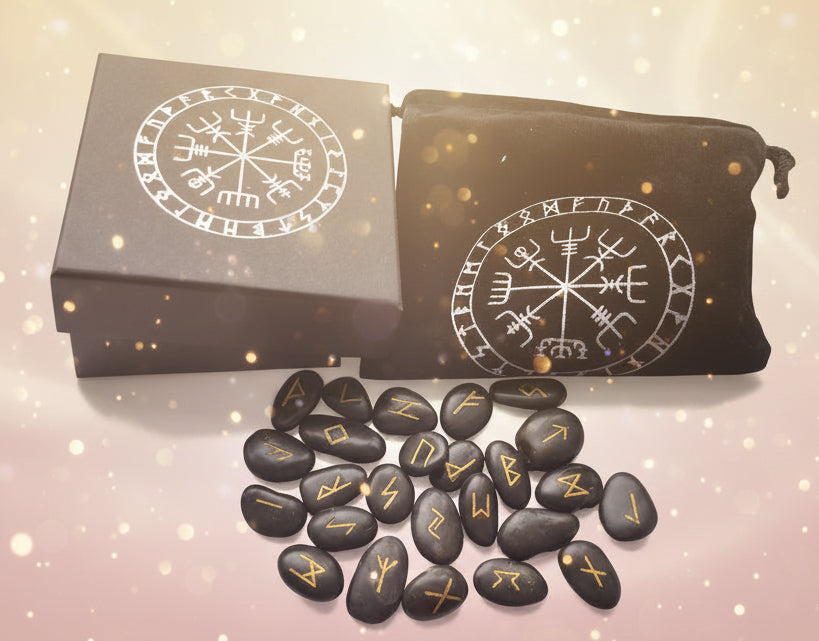 Black stones with gold runes next to a box and pouch with similar designs.