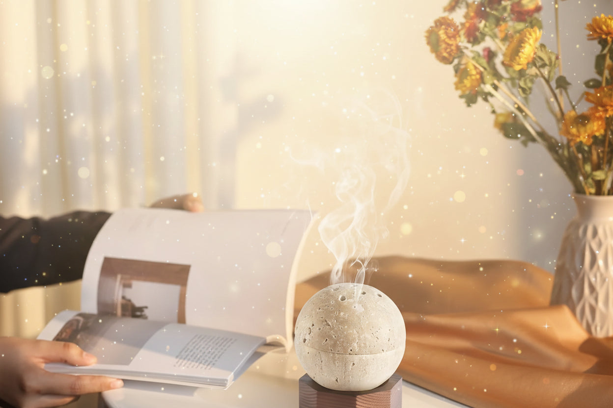 Concrete diffuser emitting steam on a table with a person reading a book and flowers in the background
