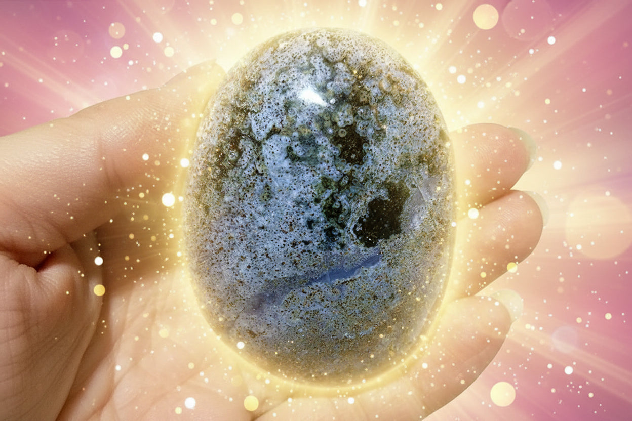 Hand holding a textured stone with a blurred green plant background