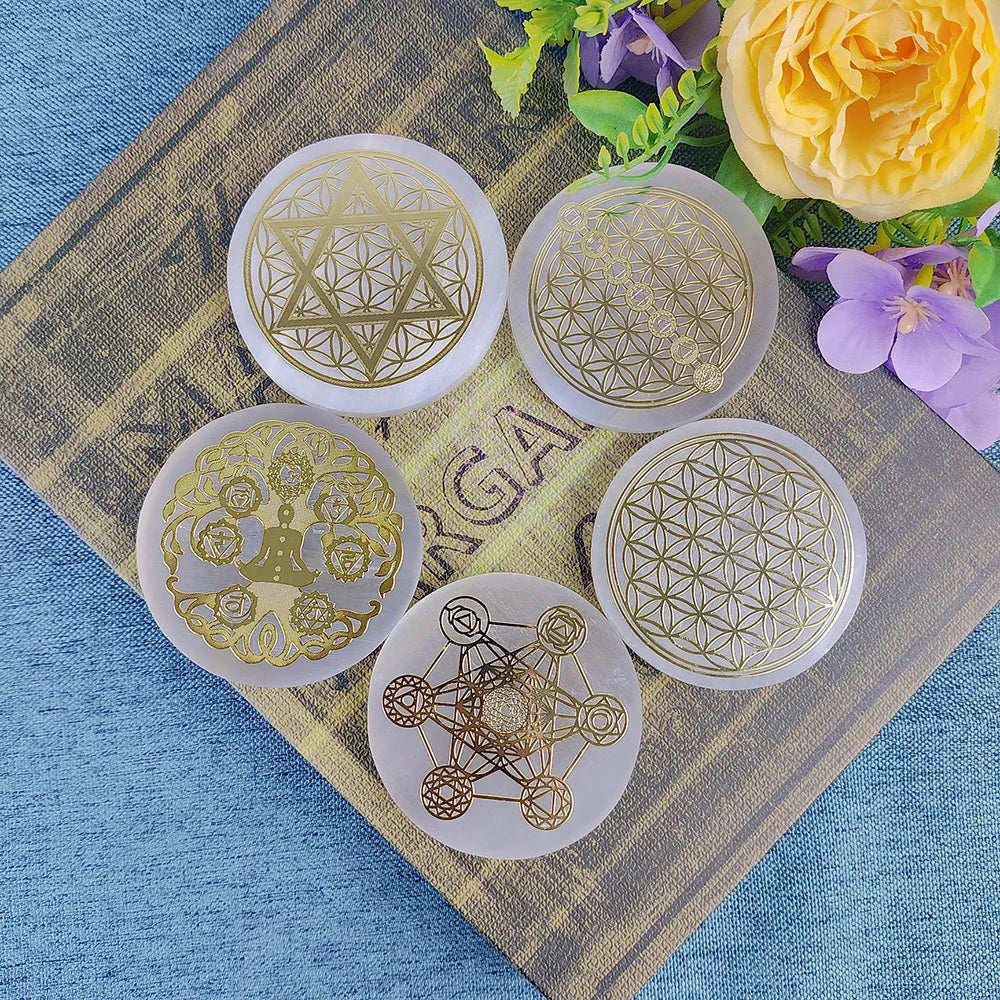 Five gold geometric designs on white circular cards on a textured surface with flowers in the background.