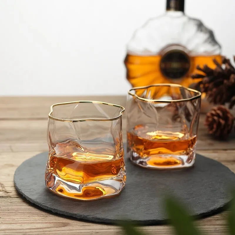 Two glasses of whiskey on a slate coaster with a bottle in the background