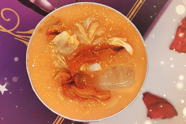 Cup of soup with ingredients on a decorative background with red petals and a candle.