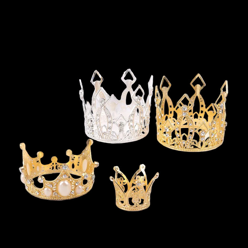 Four decorative crowns in gold, silver, and pearl on a light surface.