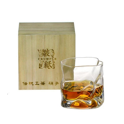 Glass of whiskey with a wooden box labeled 'Crumple' on a white background