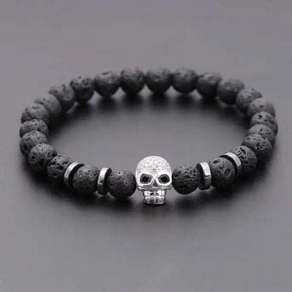 Black beaded bracelet with a silver skull charm on a gray background